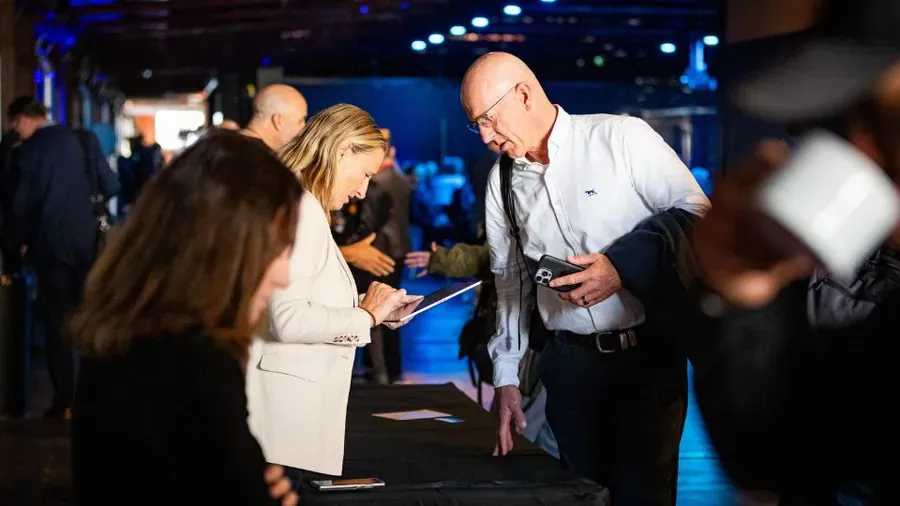 Attendees signing in on a tablet at the Roadshow registration desk